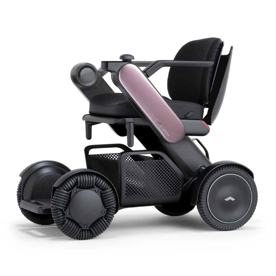 WHILL Model C2 power wheelchair with pink arm covers, front three-quarter studio view