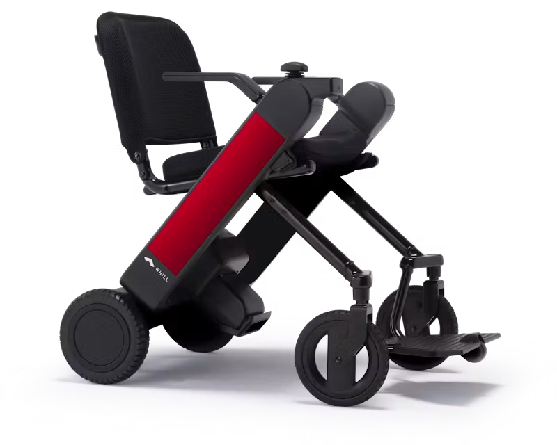 WHILL Model F power wheelchair with red arm covers, rear three-quarter studio view