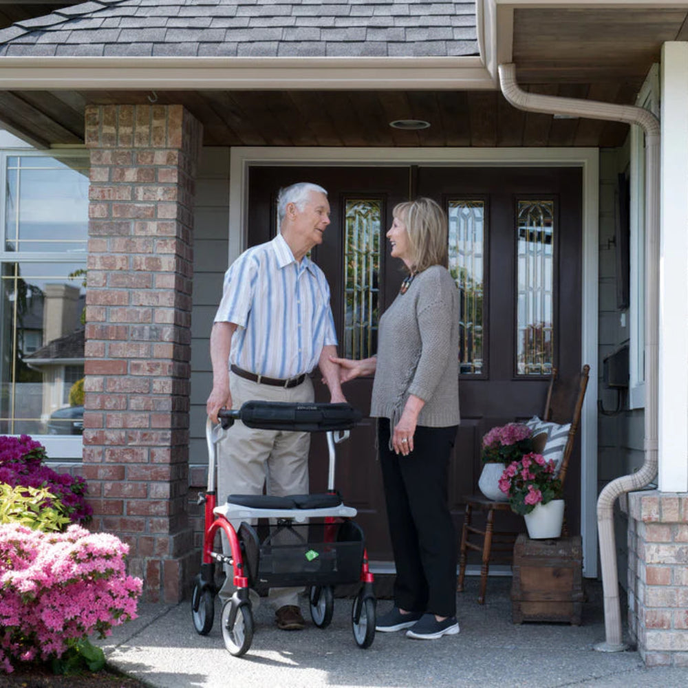 Senior couple enjoying outdoor mobility together on a residential walkway, supported by their Evolution Xpresso Lite CF rollator walkers.
