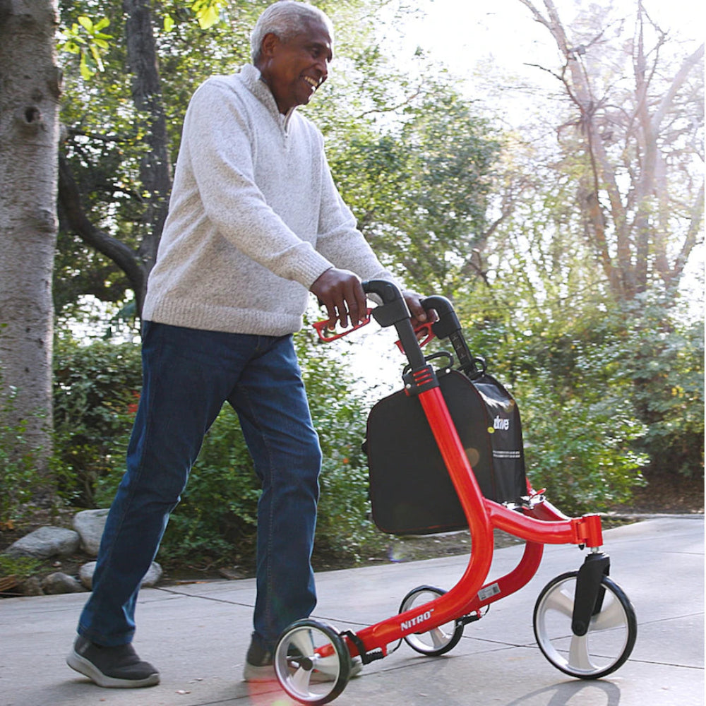 Lifestyle shot of a senior confidently walking along an outdoor path near the water using the agile Drive Medical Nitro 3-Wheel Rollator.