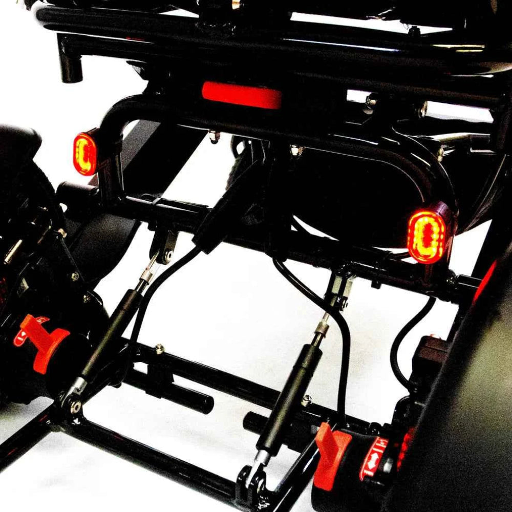 Bright red LED taillight from the Travel Buggy safety set mounted securely to the rear frame of a power wheelchair.