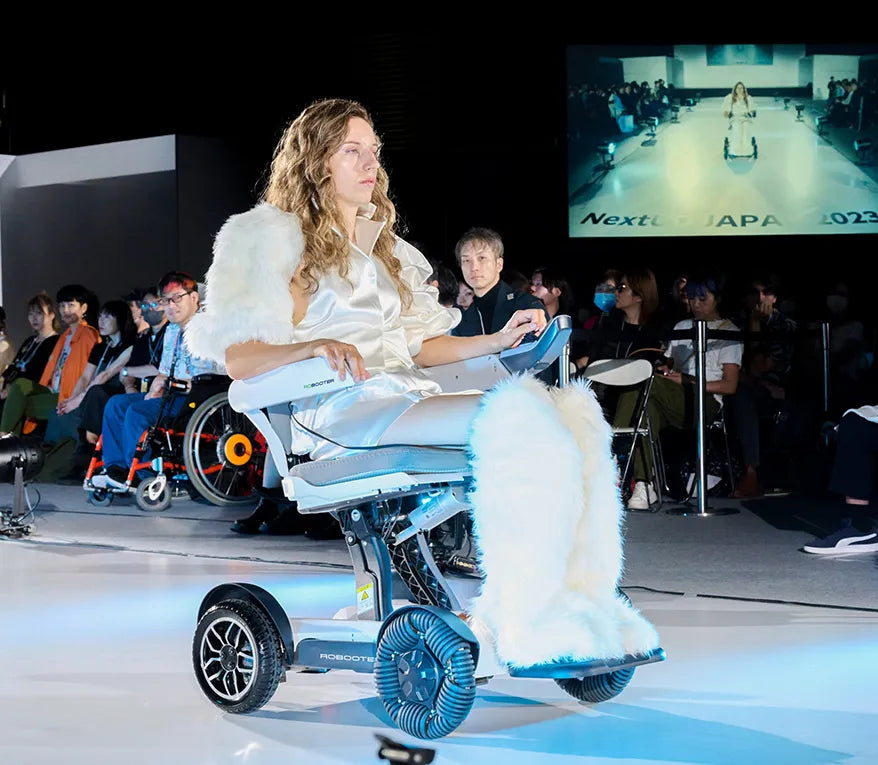 Lifestyle image of a woman navigating a spacious, modern audition hall using the sleek Robooter X40 electric wheelchair.