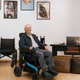 Smiling senior man using a folding electric wheelchair indoors in Canada