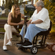 Older woman on a Travel Buggy HELIX scooter chatting with a younger woman on a park bench