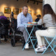 eFOLDi Navigator folding power wheelchair beside a cafe table