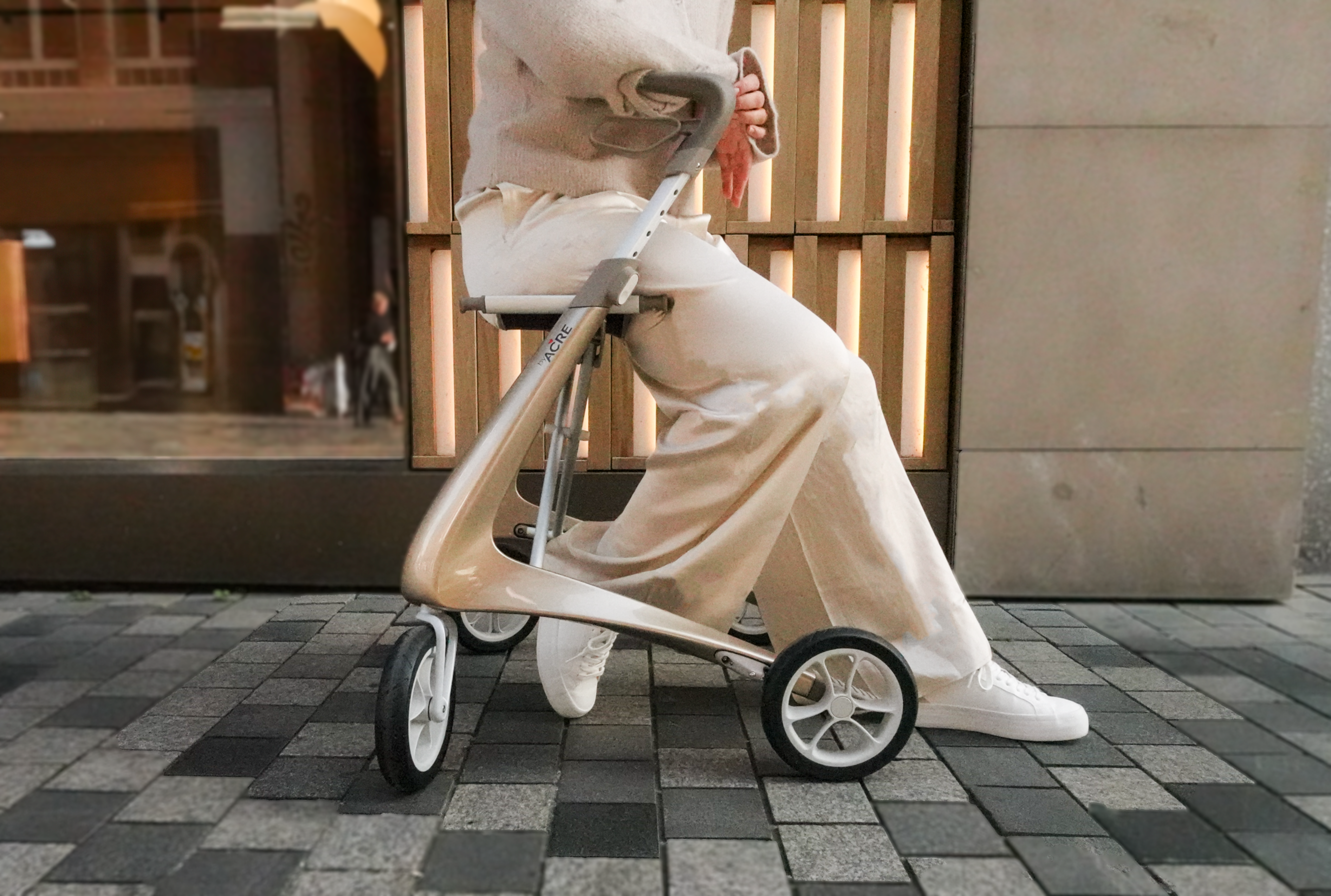 Woman resting on the seat of a Champagne Gold byACRE Carbon Ultralight rollator on a city street