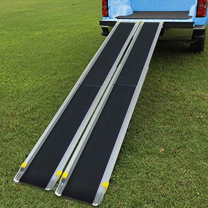 Lifestyle shot showing the telescopic wheelchair ramps securely set up on the back hatch of an SUV, providing easy access over a grassy surface.