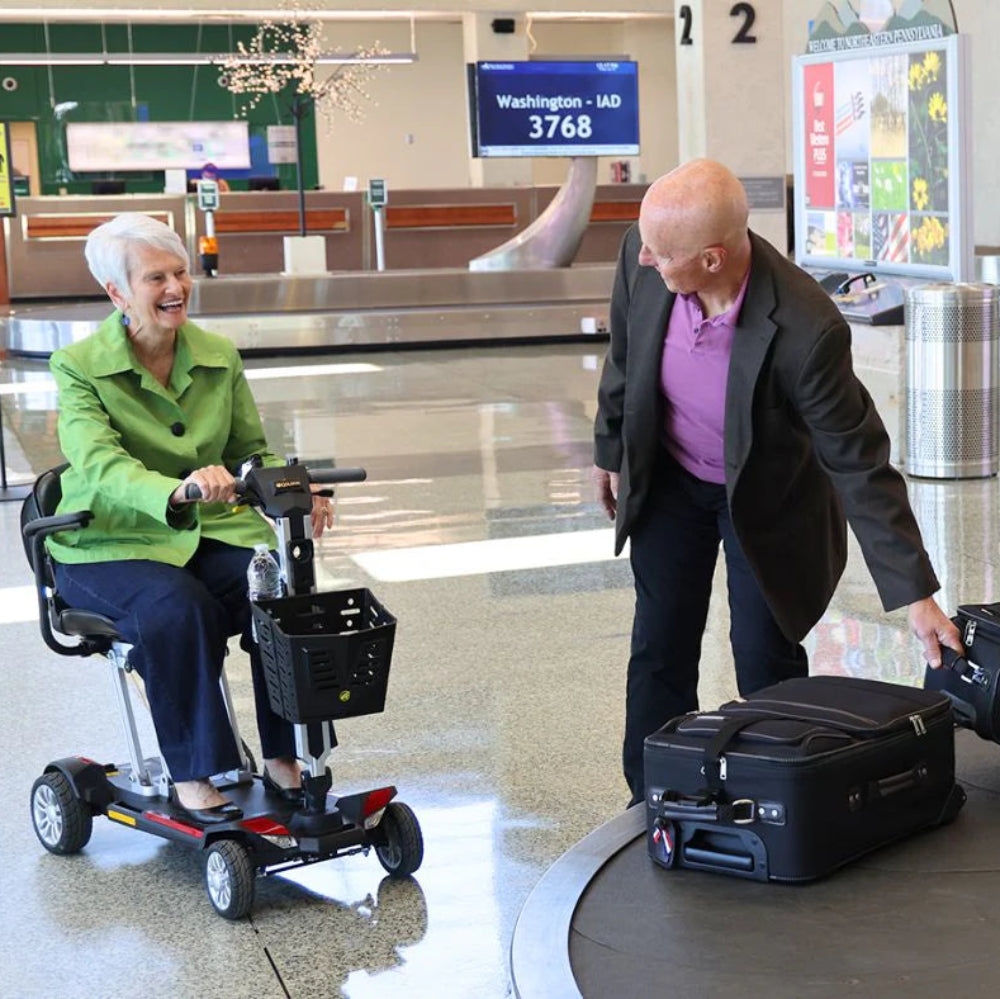 Lifestyle image of a couple navigating an airport terminal, with the man confidently driving the Buzzaround CarryOn scooter.