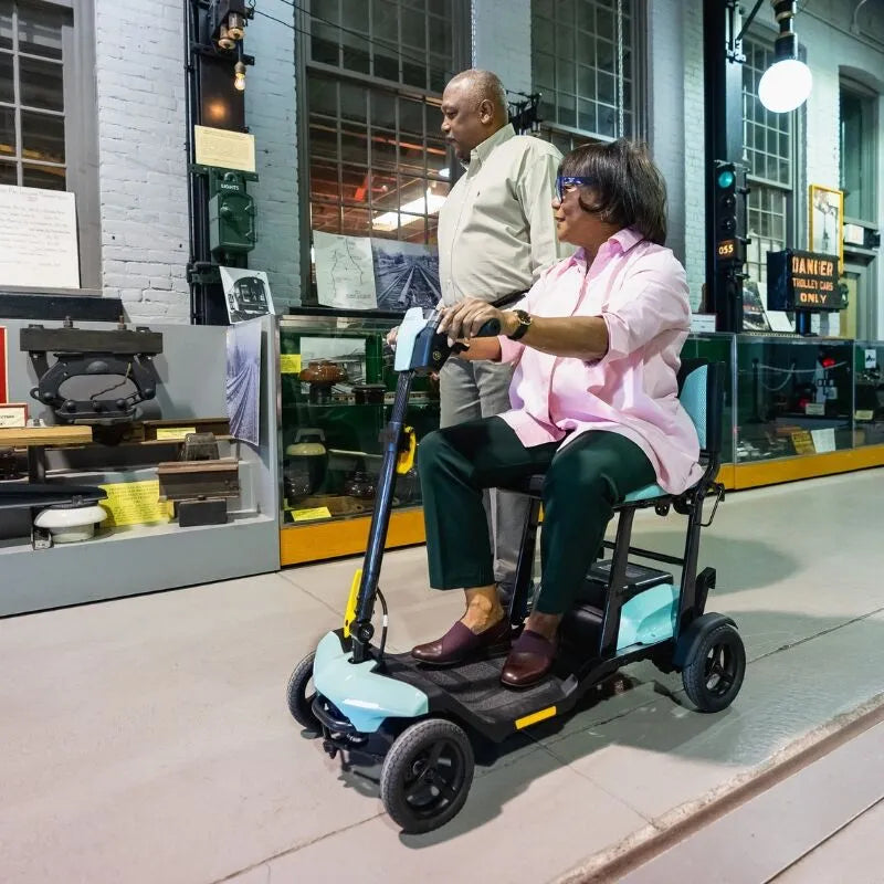 Lifestyle shot of a couple enjoying a factory, with the woman riding the Go-Go Super Portable mobility scooter.