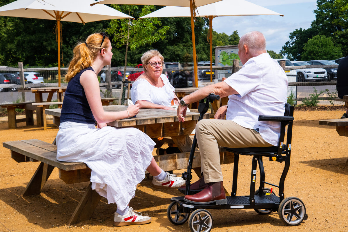eFOLDi Compass at an outdoor cafe table, shown with optional armrests