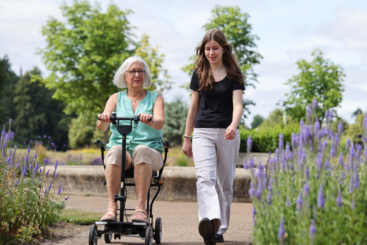 Rider using the eFOLDi Compass on a garden path, shown with optional armrests