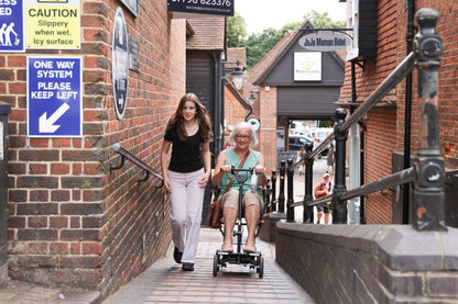 eFOLDi Compass travelling along a town pathway with a companion, shown with optional armrests