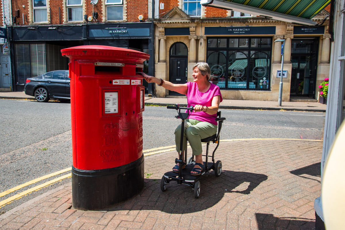 Rider on the eFOLDi Compass beside a post box, shown with optional armrests
