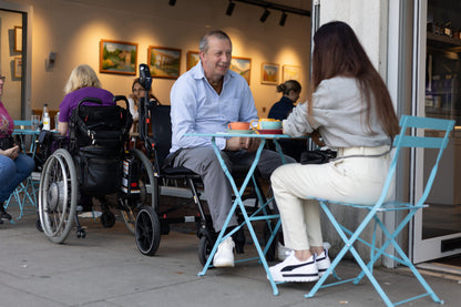 eFOLDi Navigator power wheelchair beside a cafe table