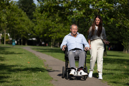 eFOLDi Navigator power wheelchair on a paved park path with a companion