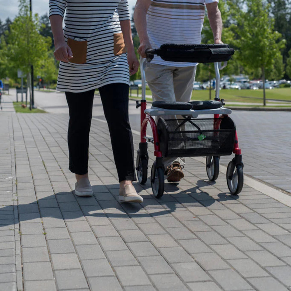 Rear view demonstrating the ease of maneuvering the Evolution Xpresso Lite CF rollator on outdoor pavement.