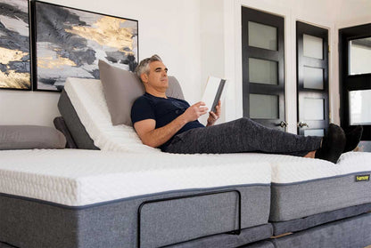 Lifestyle image of a man relaxing and reading a tablet with the head raised on the Harmony Hi-Low bed.
