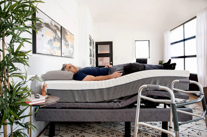 Lifestyle shot of a man elevating legs on the edge of the flat Harmony Hi-Low adjustable bed.