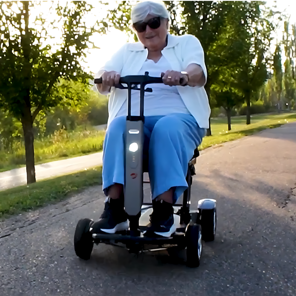 A man riding the Travel Buggy HELIX mobility scooter through a park on a sunny day, Care Made