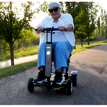 Lifestyle shot of a man enjoying a sunny day outdoors, riding the Travel Buggy HELIX scooter through a park.