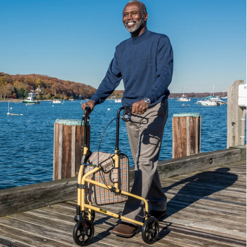Senior man confidently using the Drive Medical Winnie Lite Supreme 3-wheel rollator outdoors on a scenic waterfront walking path.