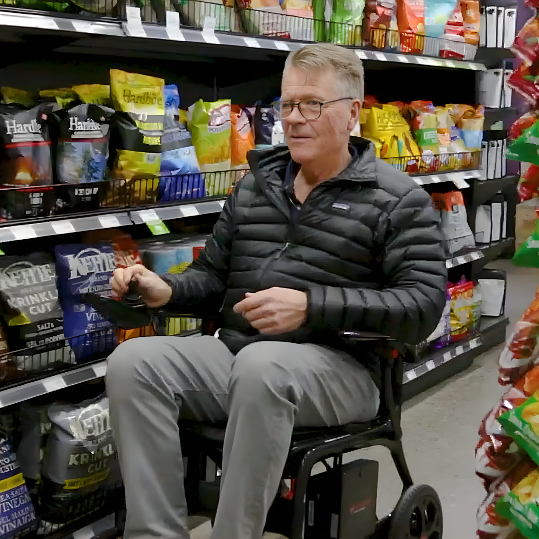 Lifestyle shot of a man easily navigating a grocery store aisle using the AEROLUX power chair.