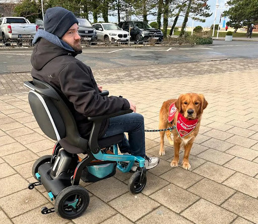 Lifestyle image of a man enjoying an outdoor walk with his dog while comfortably driving the turquoise Robooter E40 power chair.