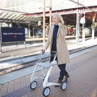 Lifestyle image of a person effortlessly navigating a paved city plaza with the beige byACRE Carbon Ultralight walker.