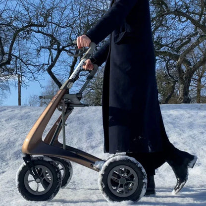 A person wearing a winter coat walking securely through snowy, icy outdoor conditions using the all-weather byACRE Carbon Overland rollator.