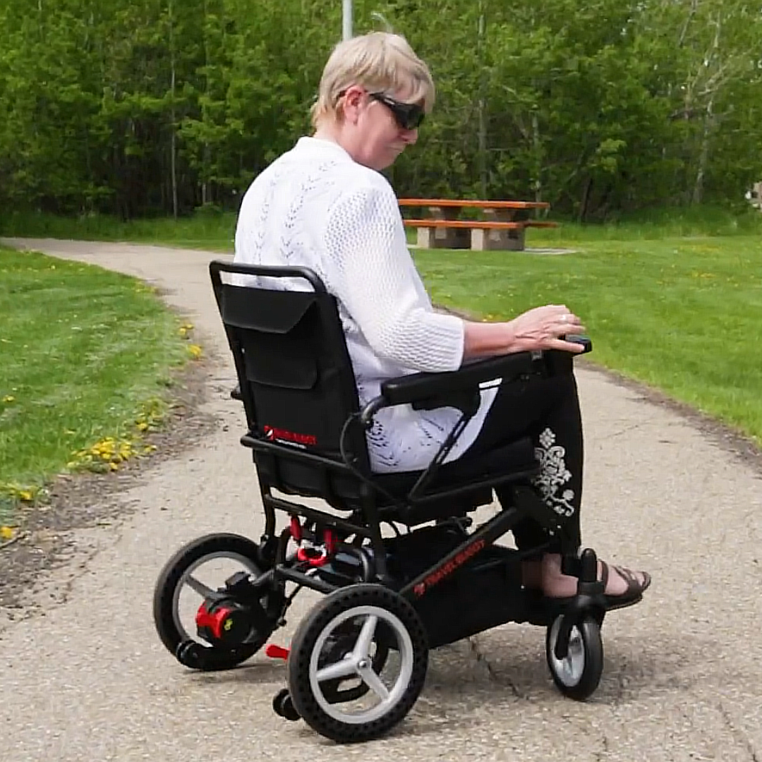 Lifestyle shot of a senior man comfortably riding the Travel Buggy Dash power wheelchair through a grassy park setting.