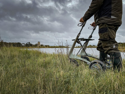 Lifestyle shot of a person confidently navigating through tall outdoor grass using the byACRE Carbon Overland all-terrain rollator.