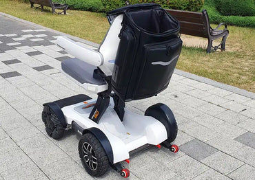 Robooter X40 backpack fitted behind a white X40 power chair outdoors, rear three-quarter view