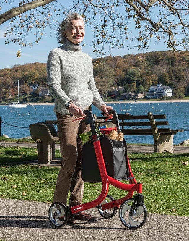 Lifestyle image of a senior taking a break on a park bench, with the red Drive Medical Nitro 3-Wheel Rollator parked conveniently nearby.