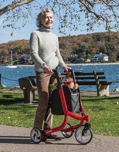 Lifestyle image of a senior taking a break on a park bench, with the red Drive Medical Nitro 3-Wheel Rollator parked conveniently nearby.