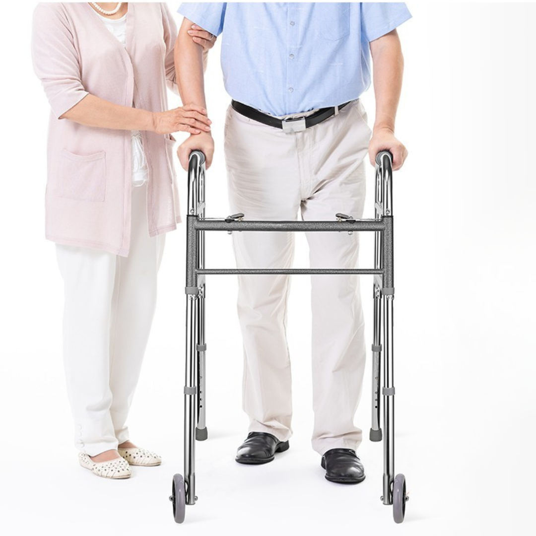 Lifestyle image of a senior user comfortably maneuvering the Care Made indoor folding walker with the helpful assistance of a caregiver.