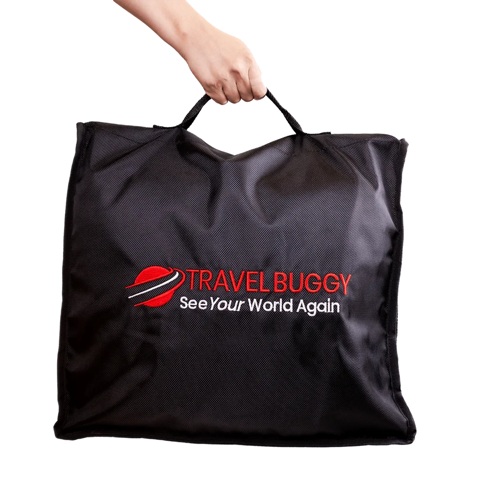 Person easily carrying the folded Travel Buggy AEROLUX 2C mobility chair using the handles of the protective travel bag.