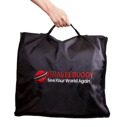 Person easily carrying the folded Travel Buggy AEROLUX 2C mobility chair using the handles of the protective travel bag.