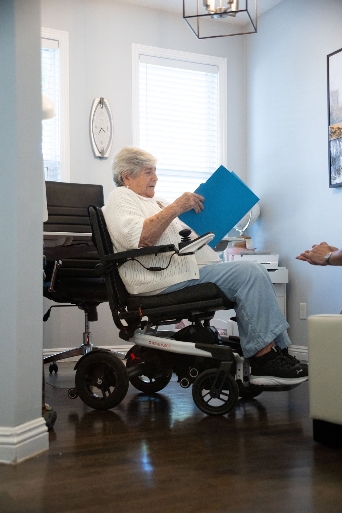 Woman using a white Travel Buggy Grand Tourer GT power wheelchair at home
