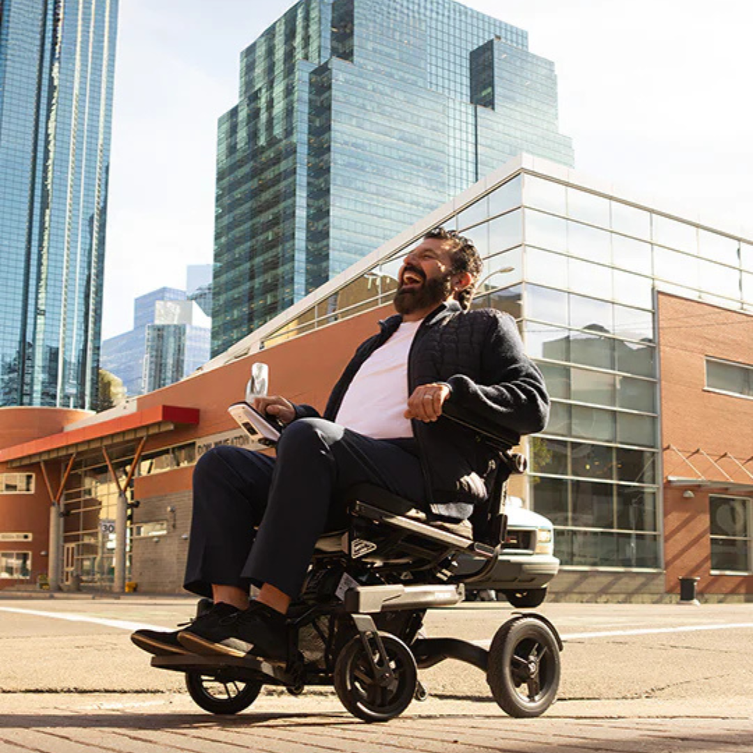 Lifestyle shot of a woman confidently driving the Travel Buggy Grand Tourer GT power wheelchair along a city waterfront.