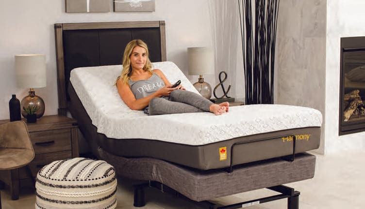 Woman comfortably relaxing on the Harmony Relax memory foam mattress while it is articulated on an adjustable bed frame.