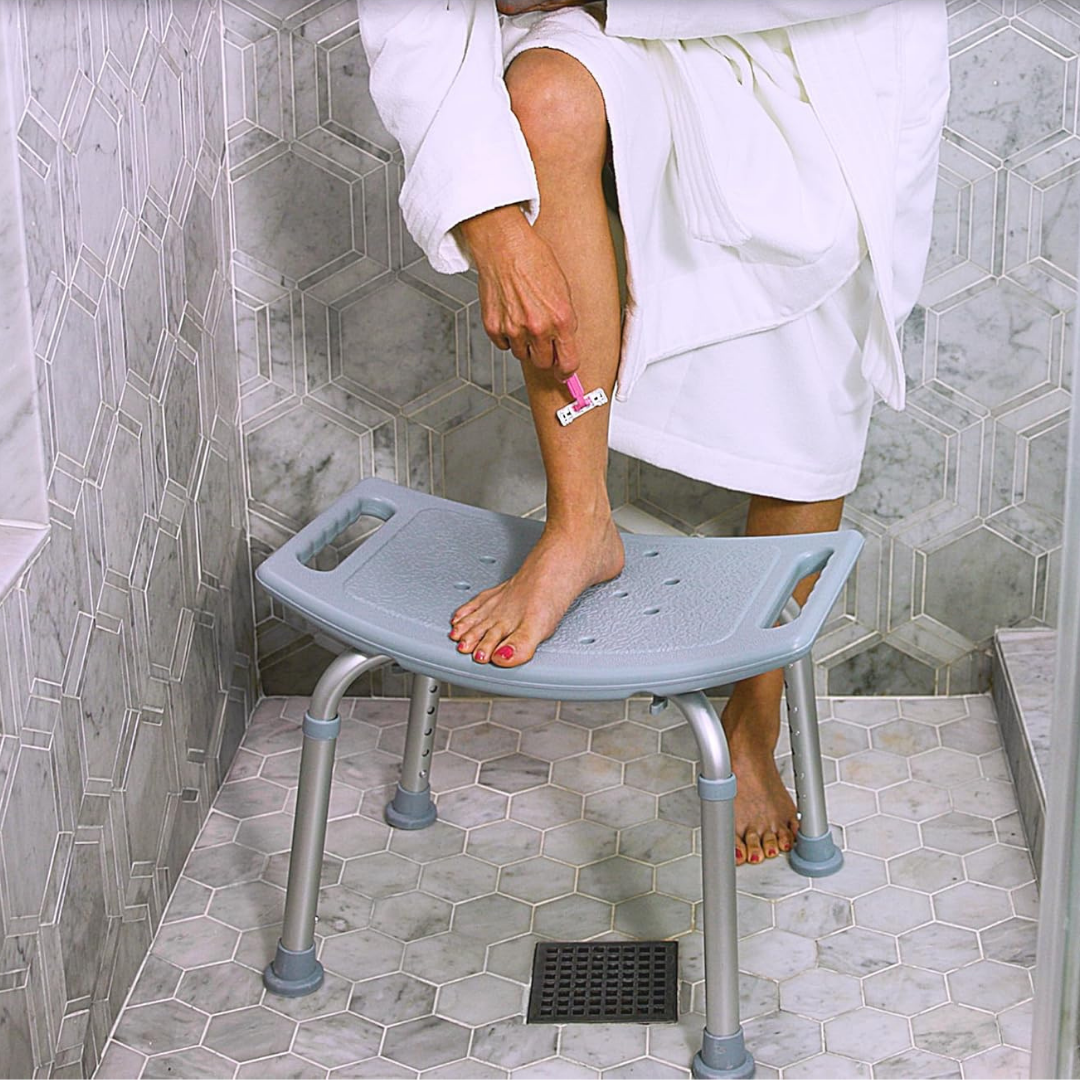 Lifestyle image showing a woman shaving her leg on the stable Drive Medical aluminum shower bench.