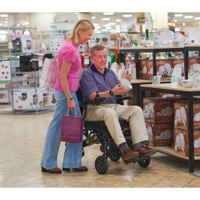 Lifestyle shot of an older couple enjoying an outdoor walk, with the woman comfortably driving the Golden Stride GP301 power chair.