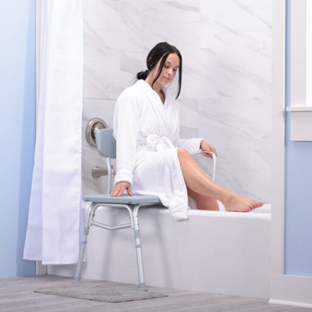 Lifestyle image of a woman safely using the Drive Medical Transfer Tub Bench in a bright, modern bathroom setting.