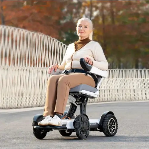 Lifestyle image of a woman easily driving the Robooter X40 smart wheelchair along an outdoor paved path.