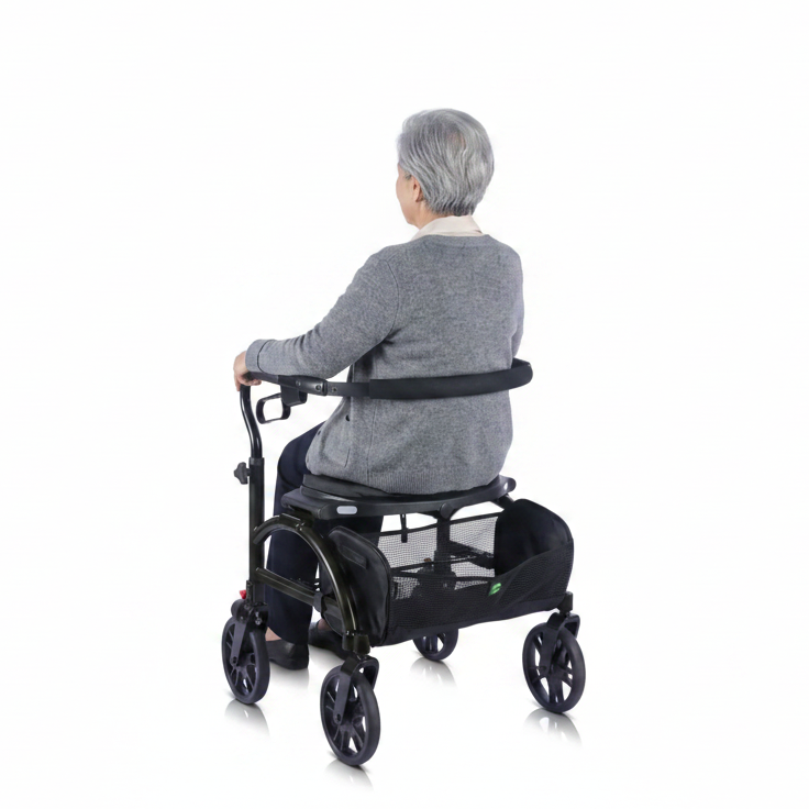 Lifestyle shot of a woman walking outdoors on a paved path from behind, supported safely by the Evolution Xpresso Wide rollator.