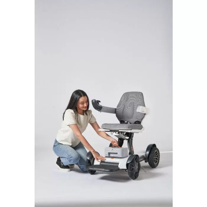 Woman demonstrating the lightweight portability and ease of handling the compactly folded Robooter X40 electric wheelchair.