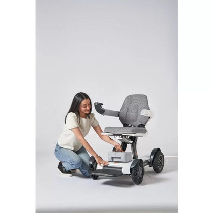 Woman demonstrating the lightweight portability and ease of handling the compactly folded Robooter X40 electric wheelchair.